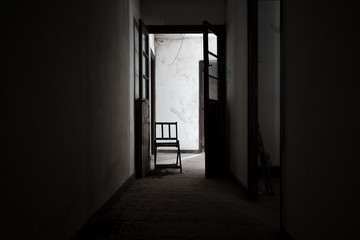 Fototapeta na wymiar Chair at the end of a dark corridor