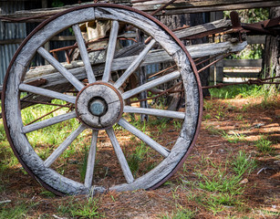 Fototapeta na wymiar An old wooden rusty waggon wheel in a rural setting