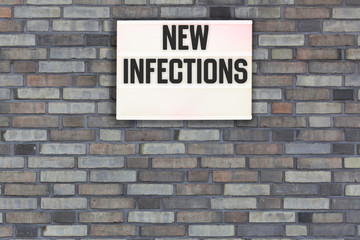 Fototapeta na wymiar New Infections words in light box letters, corona virus pandemic buzwword headline