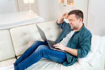 sad businessman working online lying on the couch.