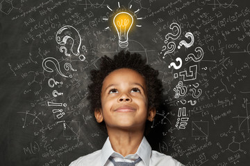 Smart kid with lightbulb. Brainstorming and idea concept. Little cute student boy on chalkboard background
