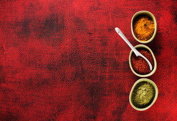 Indian spices seasoning spicy in bowls on a red background and copy space for text, top view. powder chili, turmeric curry and cardamom