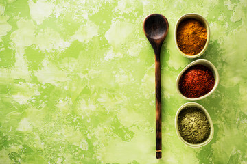 Powder spices and spicy turmeric, coriander and chili in bowls on a concrete background with copy...