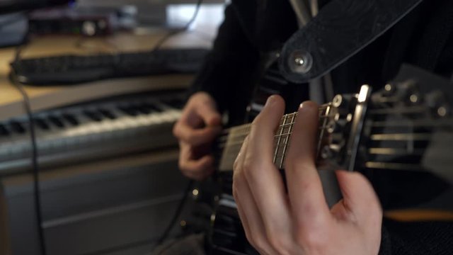 Fingers On Fretboard Strings. Close-up Hands Playing Music on Electric Guitar. Young Adult Musician Plays and Records Music at Home Studio. 2x Slow motion 0.5 speed 4K 60p