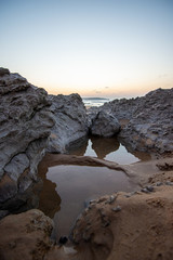 Obraz premium sunset near the sea between the rocks at the beach