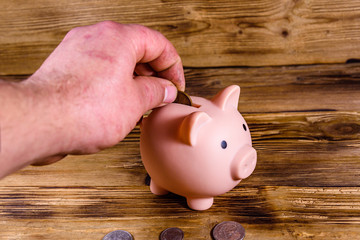 Man putting cent coin in a pink piggy bank
