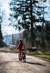 Five year old girl rides a pink bike in a forest in the mountains of German Harz