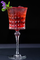 red refreshing alcoholic cocktail made from cherry juice decorated with mint and flowers