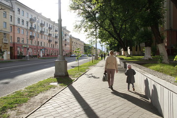 People walk through city. Mother going with dauthter along the street. City life
