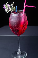red refreshing alcoholic cocktail made from cherry juice decorated with mint and flowers