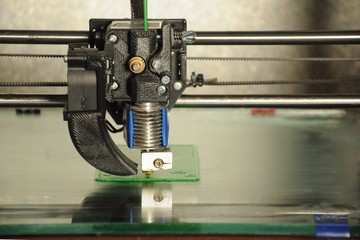 close-up 3D printer head, printing plate made of green plastic 