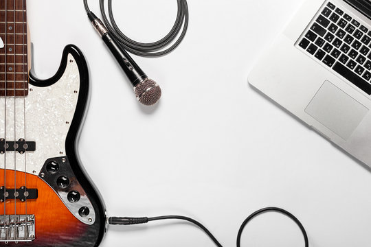 Stylish Minimalist Workplace With A Laptop, Guitar, Microphone And Glasses In A Flat Style. White Background. View From Above.