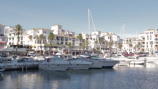 MANILVA, MALAGA / Spain - December 14 2019: Beautiful panoramic view of "Puerto de la Duquesa" Yachts and boats docked in the Harbour. Luxury Apartment Urbanisation and Restaurants. Camera Pan Right