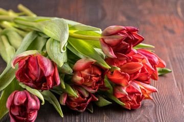 Spring tulip flowers bouquet over brown wooden background. Flat lay, copy space.
