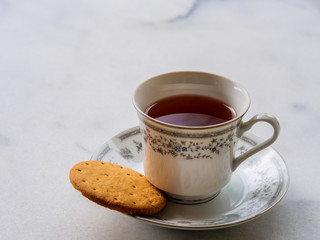 English tea in a porcelain china cup with a digestive biscuit