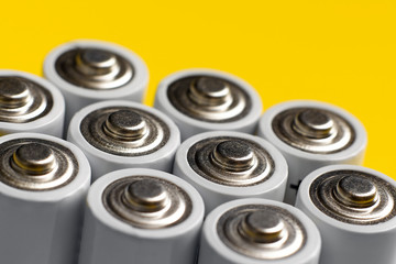 A lot of AA batteries on a bright yellow background.