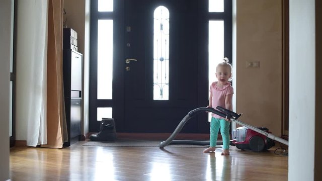 little girl trying to vacuum in the hallway at home. A comic video about helping children to their parents