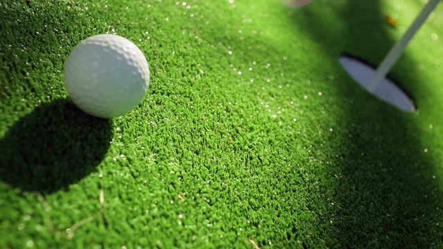 Close-up of golfer using putter to sink short putt into hole