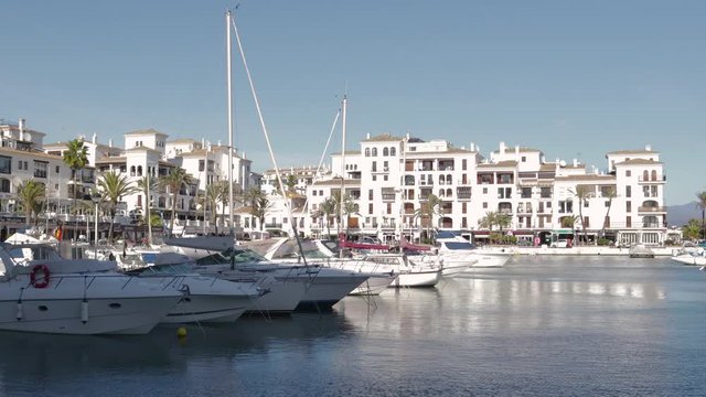 MANILVA, MALAGA / Spain - December 14 2019: Beautiful panoramic view of "Puerto de la Duquesa" Yachts and boats docked in the Harbour. Luxury Apartment Urbanisation and Restaurants. Camera Pan Right