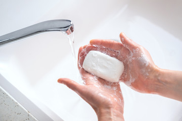 Fototapeta premium woman washes hands with soap. water flows from the tap. soap protects hands from viruses. soap in female hands