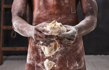 Dark skin baker man kneads Dough in the kitchen. Pastry chef prepares yeast dough for pizza pasta.