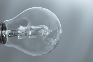 Close up on a transparent light bulb over a grey background.