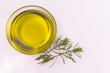 Olive oil with a sprig of rosemary in a plate on a white background. Copy space. Top view.