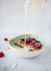 A bowl of homemade oatmeal with raspberries, chia seeds and hazelnuts