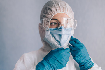 Female infectious disease specialist puts on a protective suit before work.