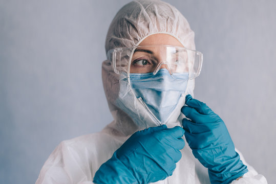 Female infectious disease specialist puts on a protective suit before work.
