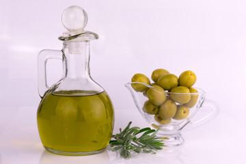 Olive oil in a decanter and rosemary with olives on a white background. Copy space.