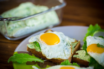 fried toast with cheese spread of arugula and fried egg in a plate
