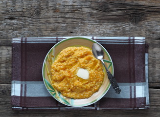 Millet porridge with pumpkin on wooden background. Healthy eating concept.