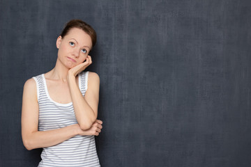 Portrait of thoughtful tired young woman propping up head with hand