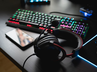 gamer work space concept, top view a gaming gear, mouse, keyboard, joystick, headset, mobile joystick, in ear headphone and mouse pad with rgb color on black table background. - obrazy, fototapety, plakaty