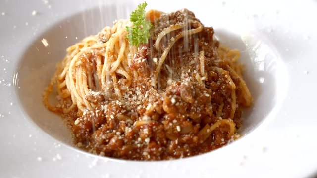 Close Up of Chef Sprinkles Parmesan on Pasta Bolognese on White Plate in Restaurant. Putting Cheese on Spaghetti with Tomato Sause
