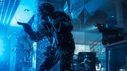 Masked Squad of Armed SWAT Police Officers Storm a Dark Seized Office Building with Desks and Computers. Soldier Breaks a Glass with His Arm and Team Continue to Move and Cover Surroundings.