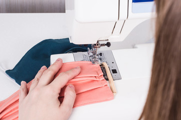 Woman hands using the sewing machine to sew the face mask during.the coronavirus pandemia..Home made diy protective mask against virus. Preventive gear in quarantine for coronavirus