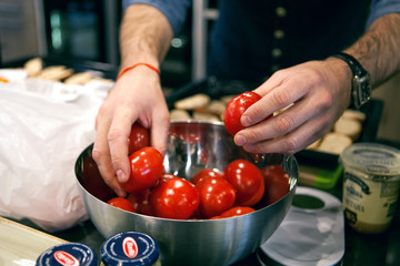 Man holding red tomatoes under the bowl during his cooking 