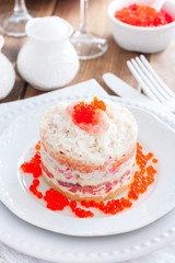Holiday salad with red fish, shrimp, crab sticks, vegetables and red caviar, selective focus