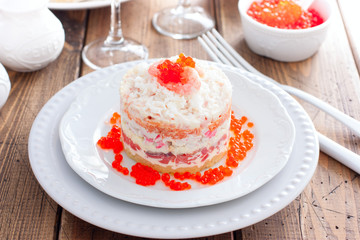 Holiday salad with red fish, shrimp, crab sticks, vegetables and red caviar, selective focus