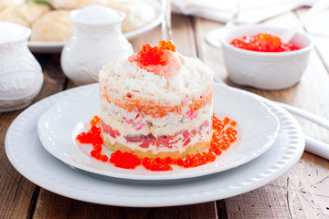 Holiday salad with red fish, shrimp, crab sticks, vegetables and red caviar, selective focus