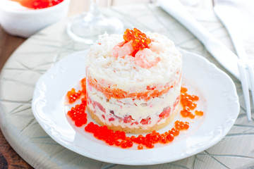 Holiday salad with red fish, shrimp, crab sticks, vegetables and red caviar, selective focus