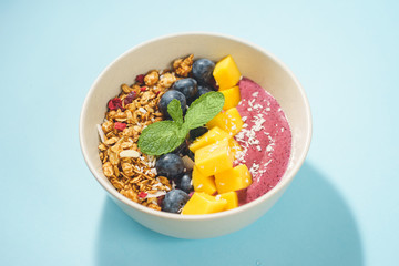 Handmade Bowl healthy tasty breakfast of yogurt, smoothie with granola, nuts, mango and berries.
