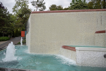 Fresh pond and fountain with white wall in front of public park , background , copy space