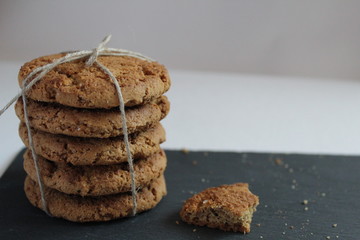 oatmeal homemade cookies are stacked on top of each other on a gray stone table on a white background side view