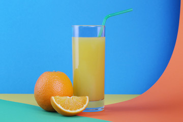 Glass of orange juice and oranges on a colorful background