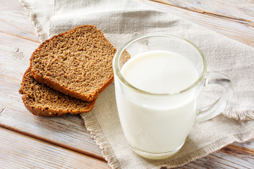 A glass of milk and sliced bread on the old white wood table. Concept of diet food, healthy nutrition, weight loss. Selective soft focus.