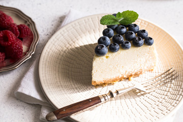 Slice Of Classical New York Cheesecake with blueberries On White Plate. Closeup View. Home bakery concept