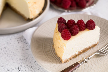 Slice Of Classical New York Cheesecake with raspberries On White Plate. Closeup View. Home bakery concept